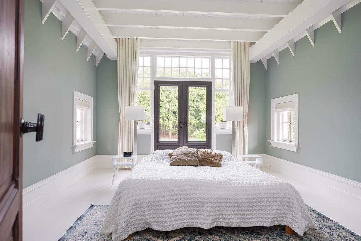 Slaapkamer met saliegroene wanden en de witte kapconstructie in het zicht