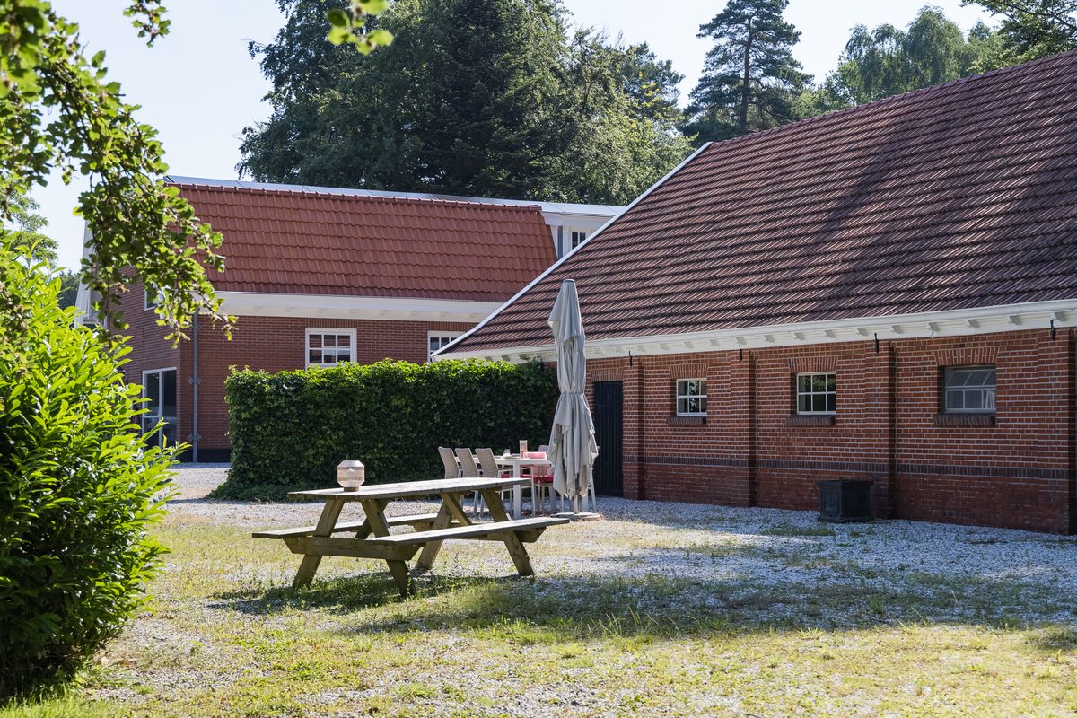 De binnenplaats achter de woonboerderij, met picknicktafel op het grind