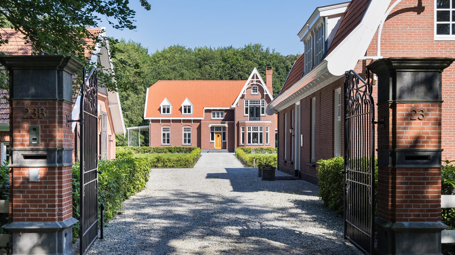 Het zicht door de open toegangspoort op de oprijlaan en het landhuis