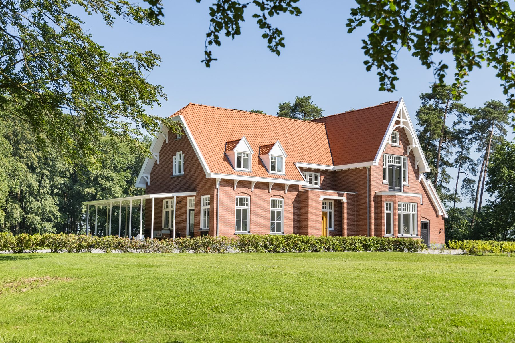 Het landhuis vanaf het gazon aan de tuinzijde, met de veranda over de volle breedte