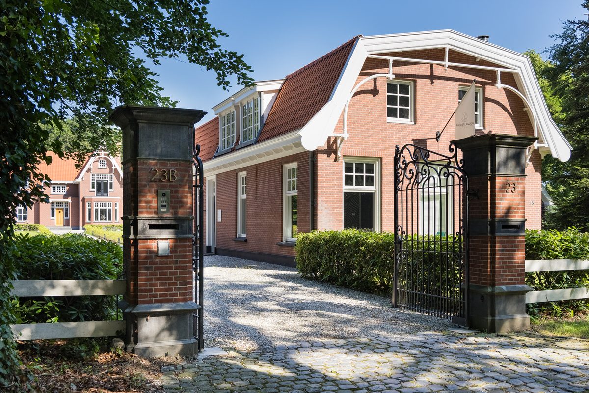 De toegangspoort met het huisnummer, met daarachter De Loods en het landhuis
